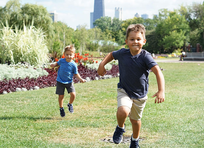 young boys running through a grassy park