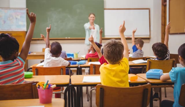 students raise their hands in a classroom