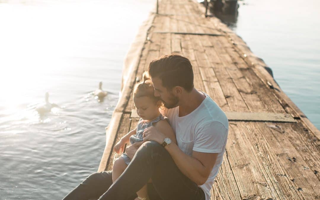 a Father sits on a lake pier with his daughter on fathers day