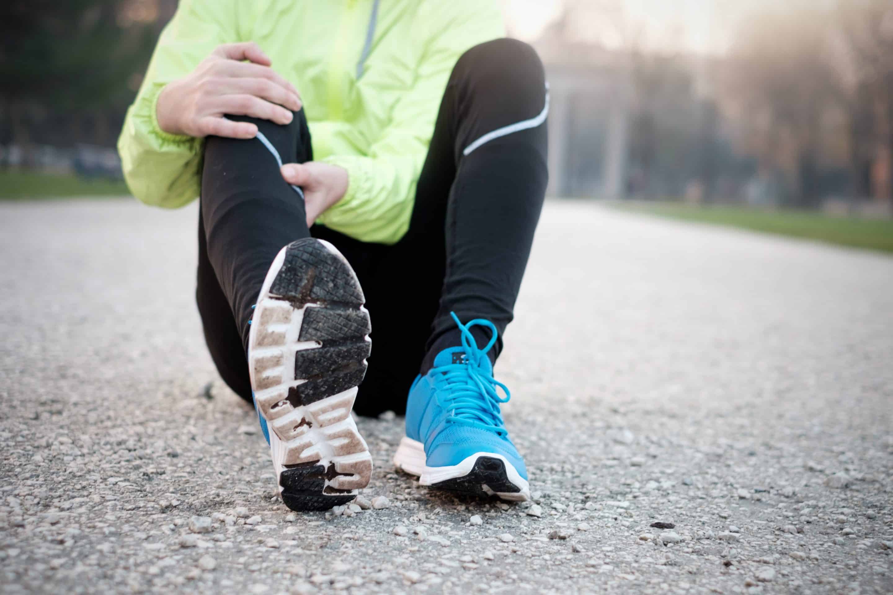 Runner with injured ankle while training in the city park in cold weather