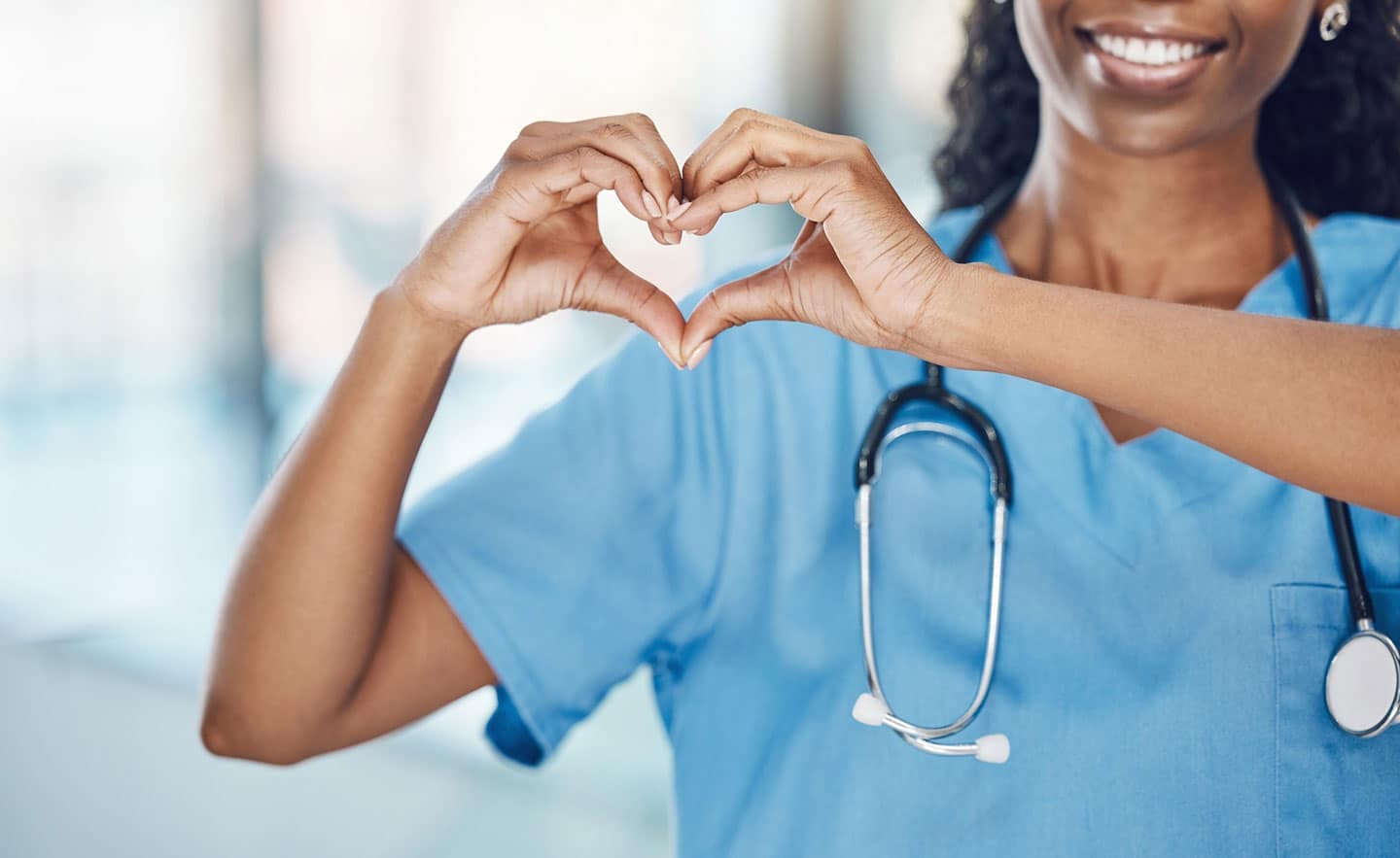 Female nurse making heart shape with her hands.