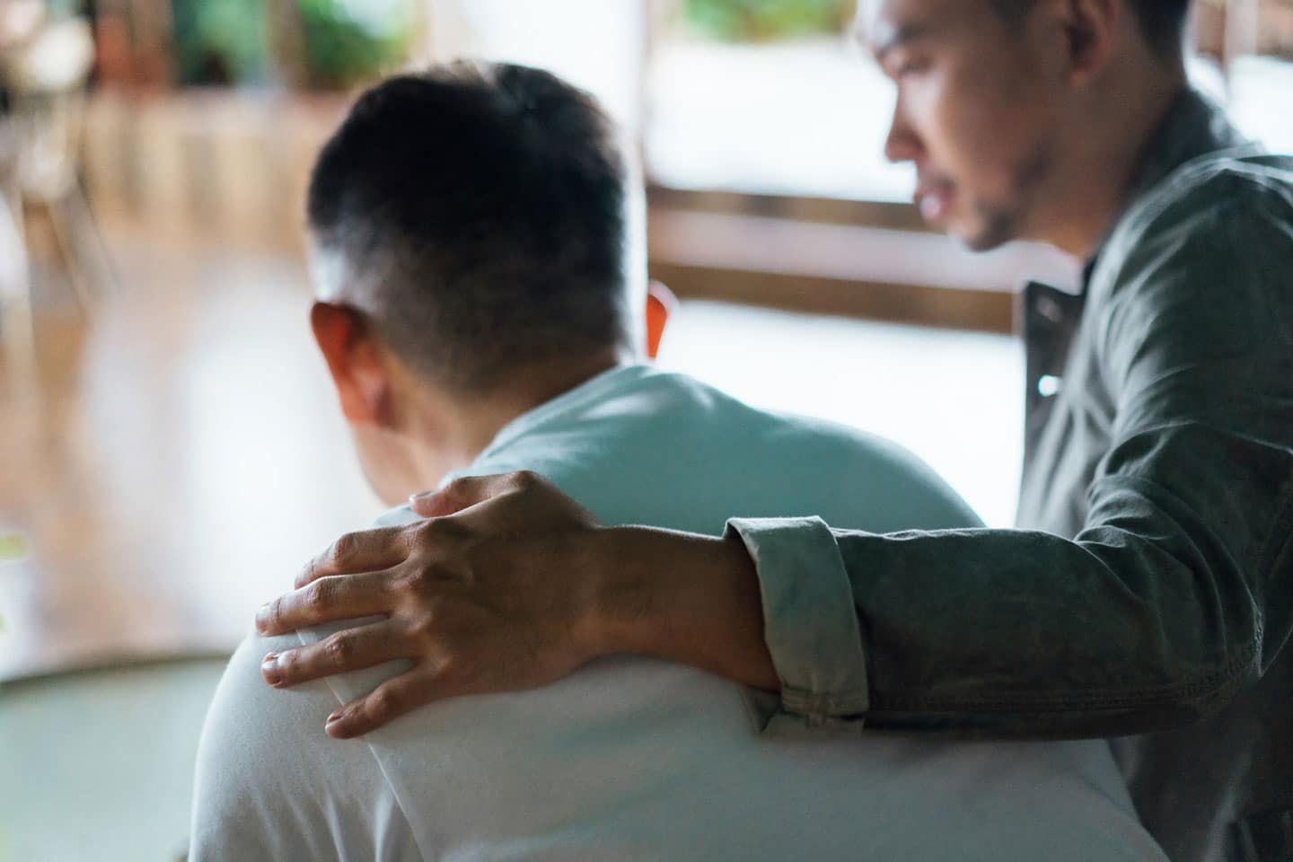 Man comforting another man.