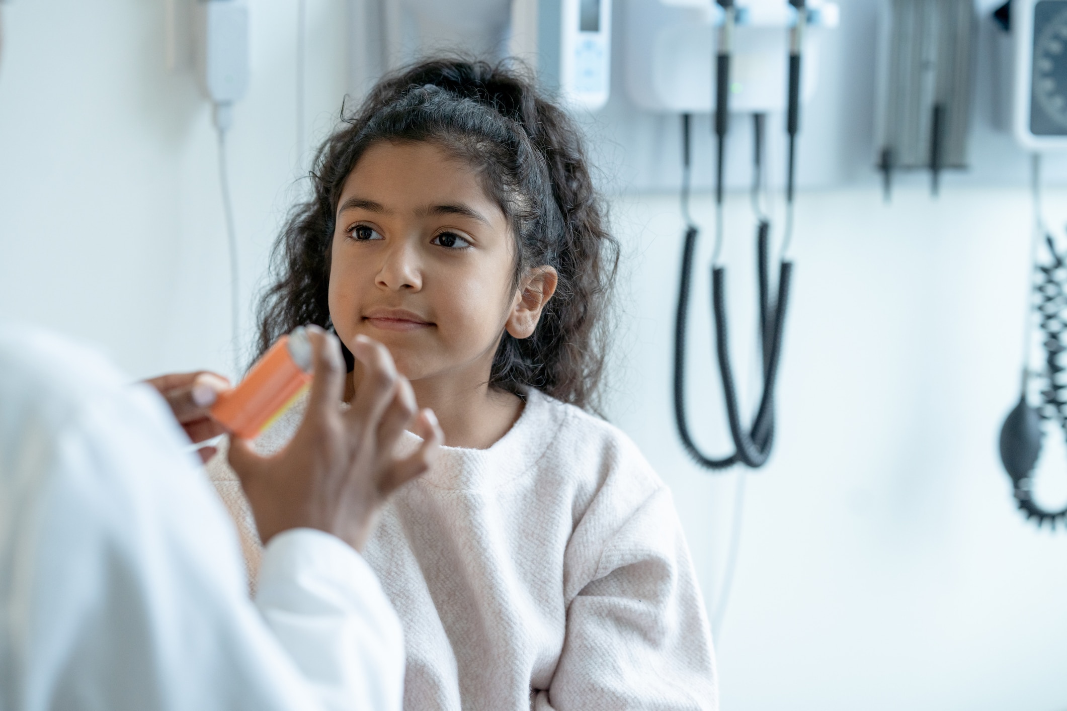 doctor handing an inhaler to a young girl patient who has asthma