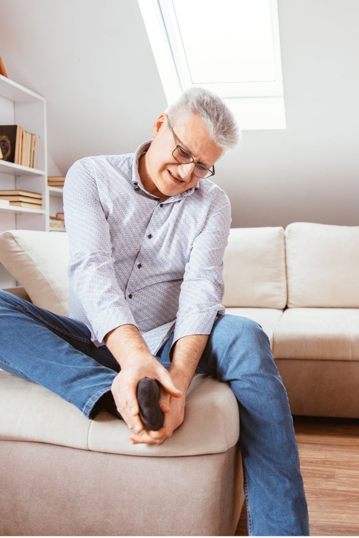 man holding his foot while suffering from chronic foot pain