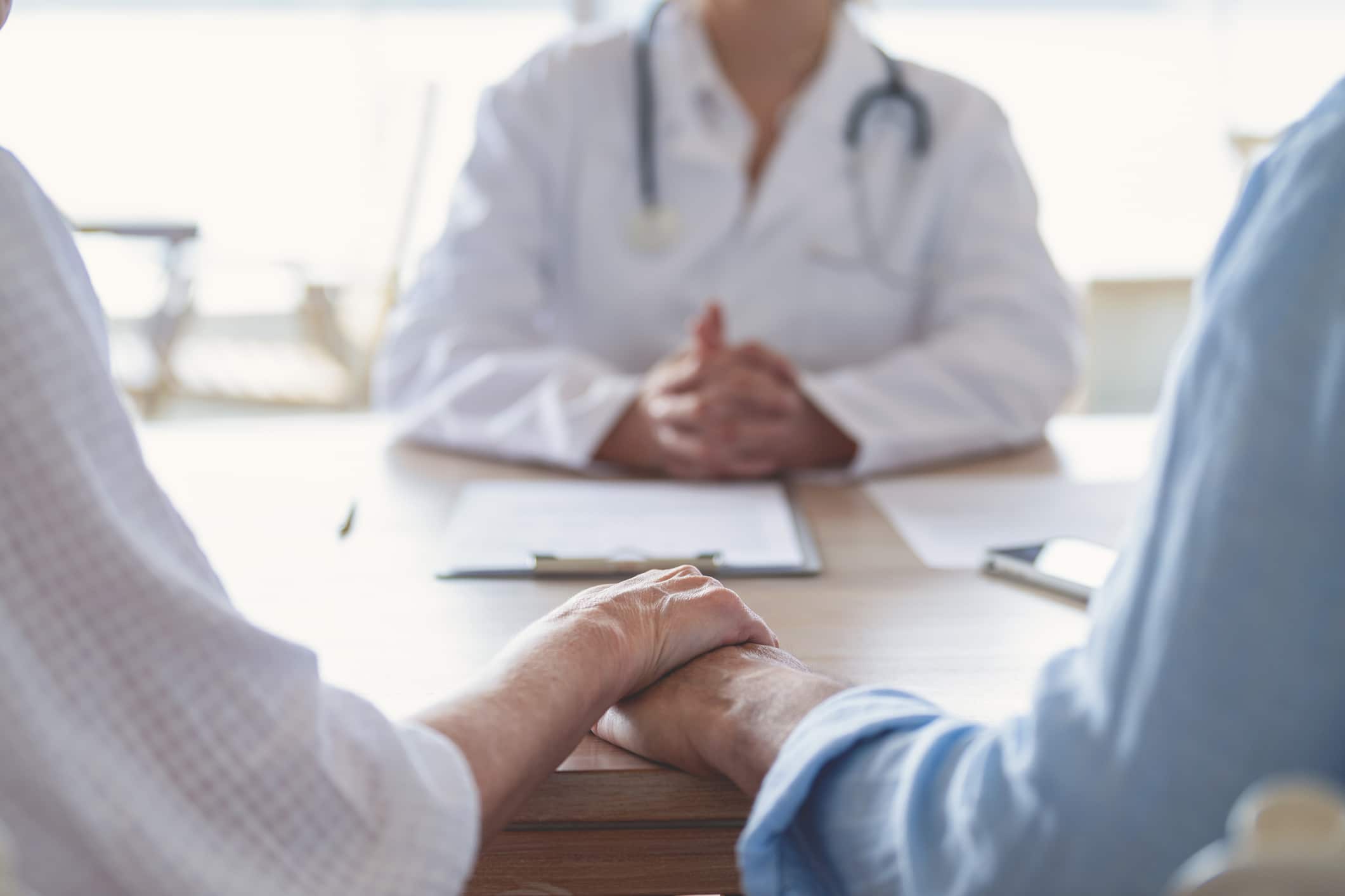 a couple sits in front of a doctor to discuss infertility options