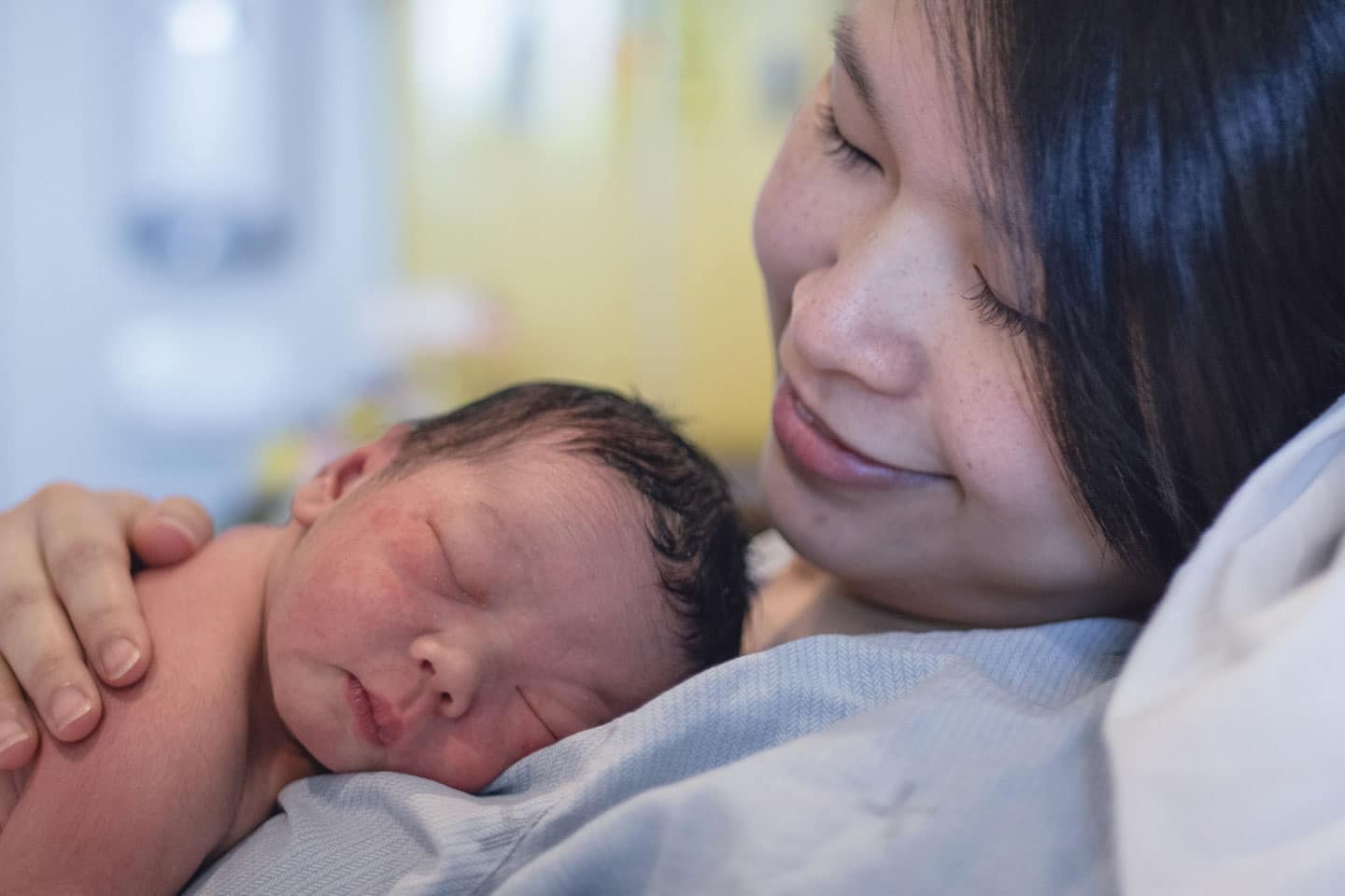 Mother holding infant laying on her chest.